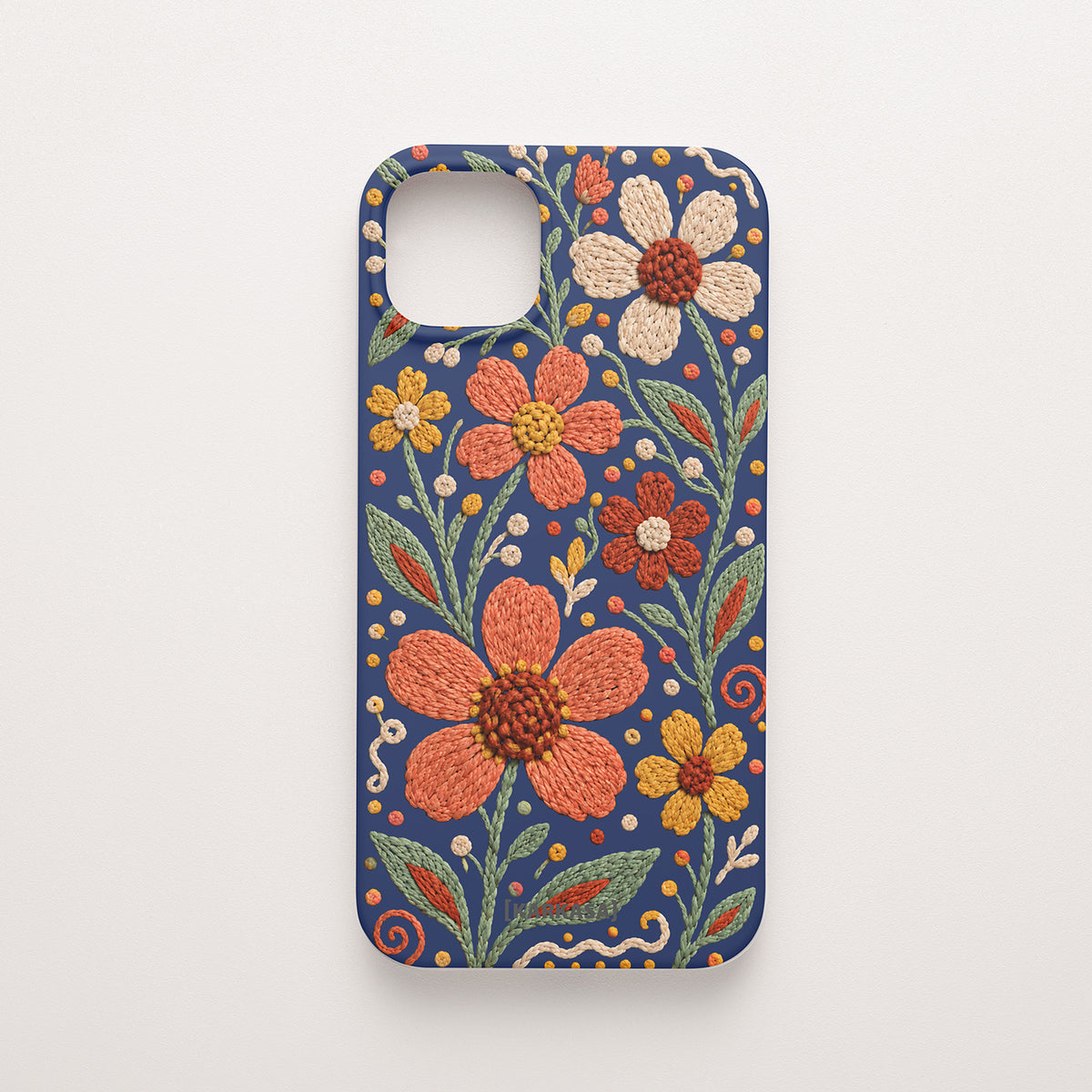 Funda de móvil de silicona azul marino con flores y hojas con efecto bordado en tonos coral, mostaza, crema y verde. Jardín Bordado, diseño original de KARKASA.
