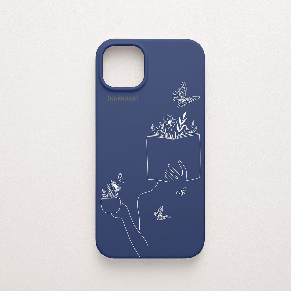 Funda de móvil KARKASA con ilustración lineal blanca de una figura leyendo con flores y mariposas, en silicona mate Silk Touch azul marino.