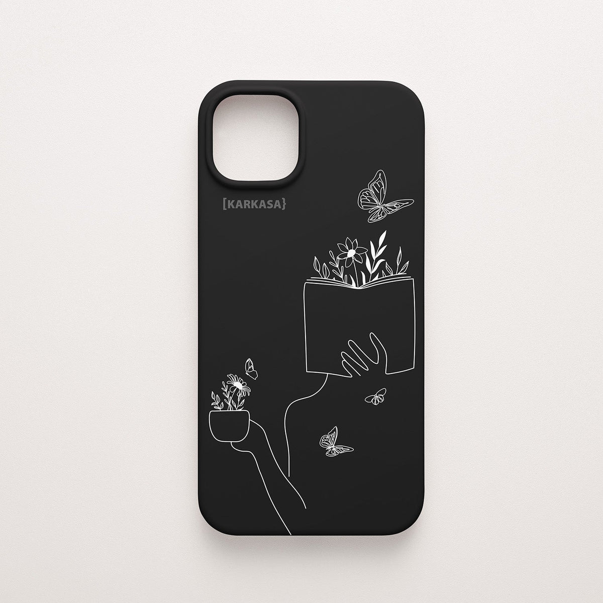 Funda de móvil KARKASA con ilustración lineal blanca de una figura leyendo con flores y mariposas, en silicona mate Silk Touch negra.