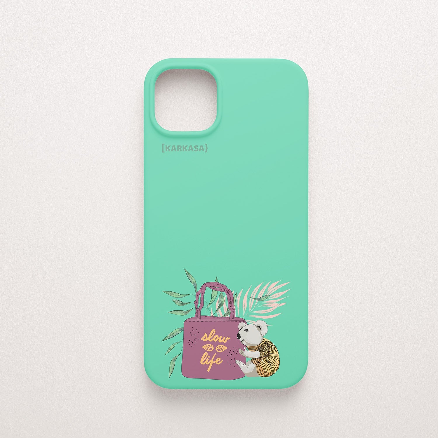Funda KARKASA Silk Touch verde menta con ilustración de koala llevando un bolso rosa con la frase Slow Life y hojas tropicales. Carcasa estilo mindfulness.