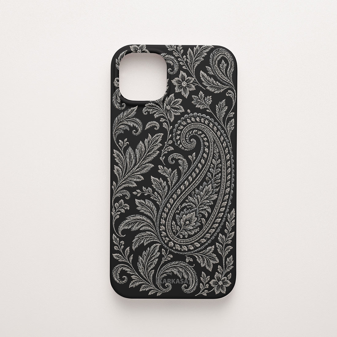 Funda de móvil de silicona negra con un gran paisley rodeado de hojas y flores en tonos plata. Paisley Plata, diseño original de KARKASA.