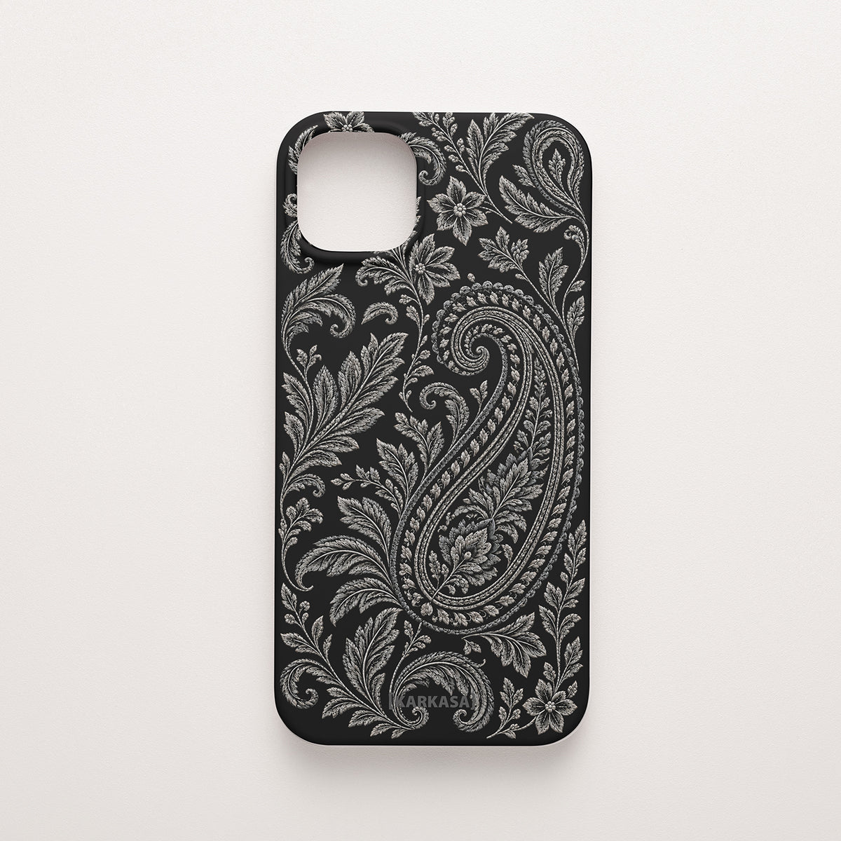 Funda de móvil de silicona negra con un gran paisley rodeado de hojas y flores en tonos plata. Paisley Plata, diseño original de KARKASA.