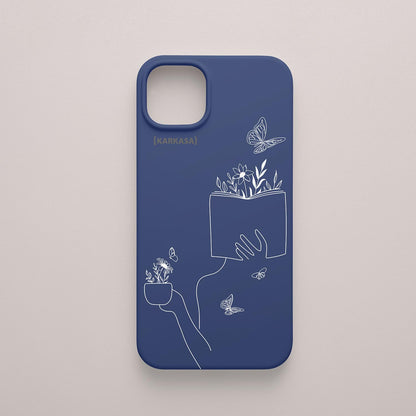 Funda de móvil KARKASA con ilustración lineal blanca de una figura leyendo con flores y mariposas, en silicona mate Silk Touch azul marina.